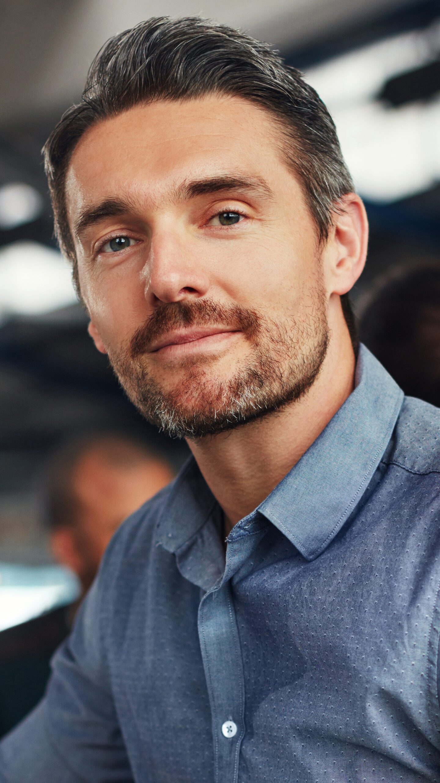Portrait, leader and business man at meeting for coworking opportunity, pride or experience. Face, professional entrepreneur or project manager working with creative team planning at startup office Man in blue button up shirt looking at camera